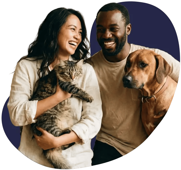Smiling pet parents holding their cat and dog at home